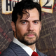Henry Cavill stares at the camera while wearing a grey striped suit.
